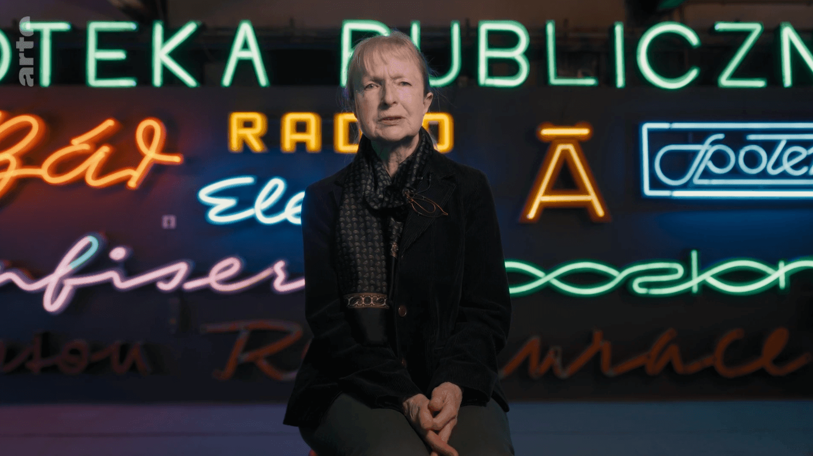 Reportaż ARTE o polskich neonach – kadr z reporterką na tle neonów Neon Studio