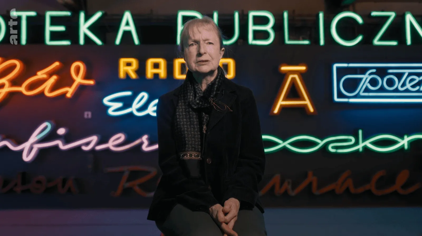 Reportaż ARTE o polskich neonach – kadr z reporterką na tle neonów Neon Studio
