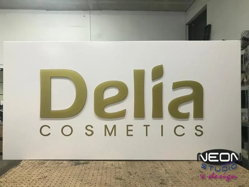 Delia Cosmetics — kaseton ze złotymi literami przestrzennymi na białym licu, w naszej pracowni