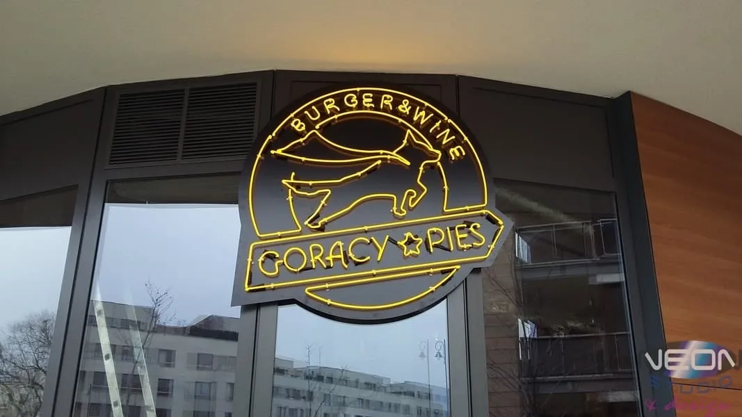 The Gorący Pies — Burger & Wine restaurant logo made in yellow glass neon, on the venue’s glazed shopfront