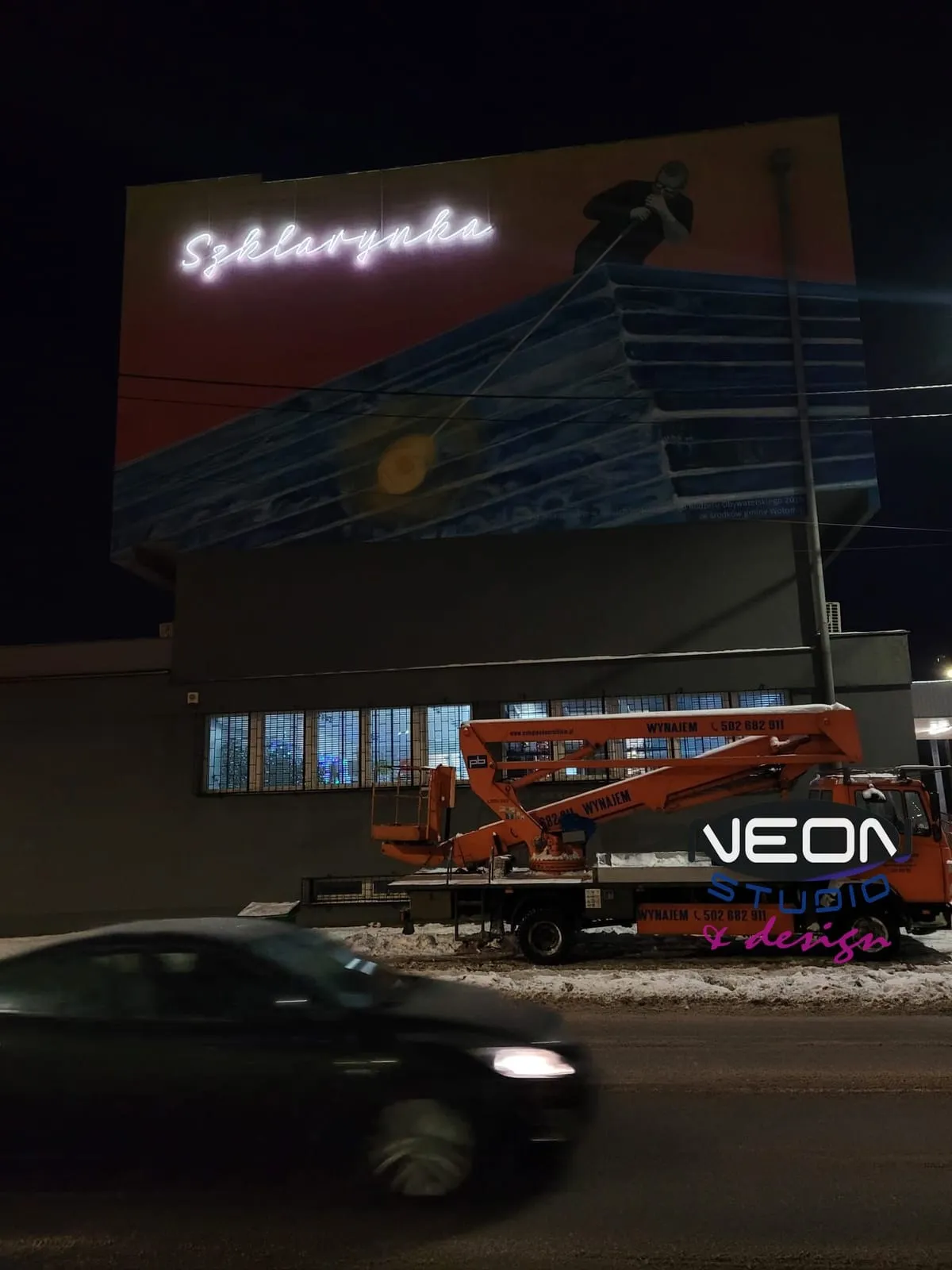 The “Szklarynka” neon on a building wall — installed from a boom lift; the same equipment and certification are needed for servicing